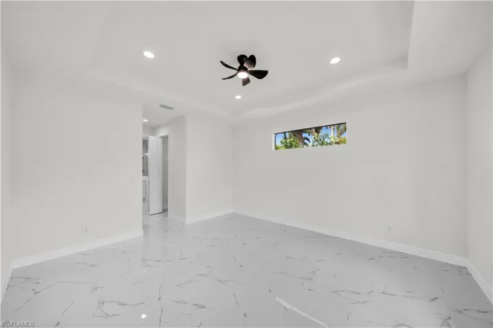 Unfurnished room with a tray ceiling, baseboards, and ceiling fan