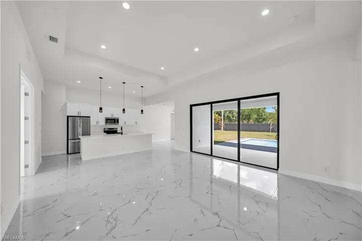 Unfurnished living room featuring a raised ceiling, visible vents, baseboards, and recessed lighting