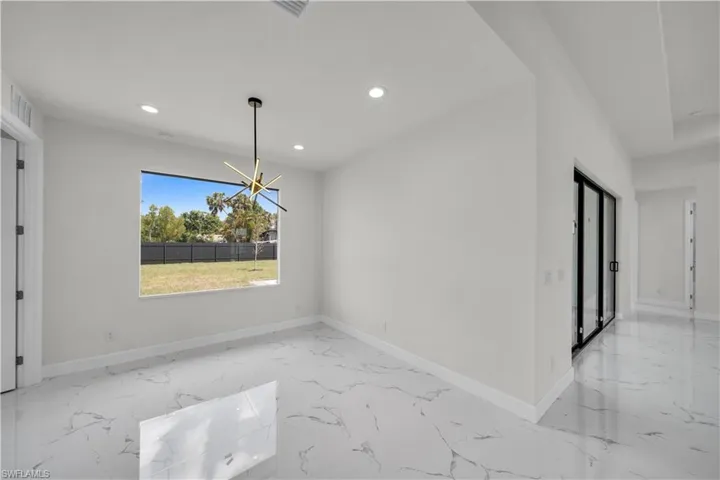 Unfurnished dining area featuring baseboards, marble finish floor, recessed lighting, and a notable chandelier