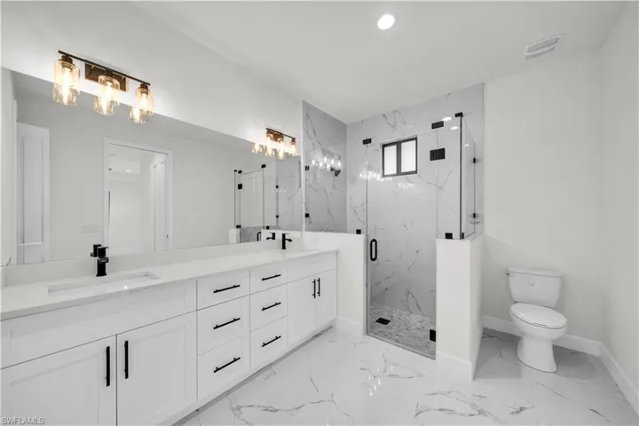 Bathroom with marble finish floor, a sink, a marble finish shower, and visible vents