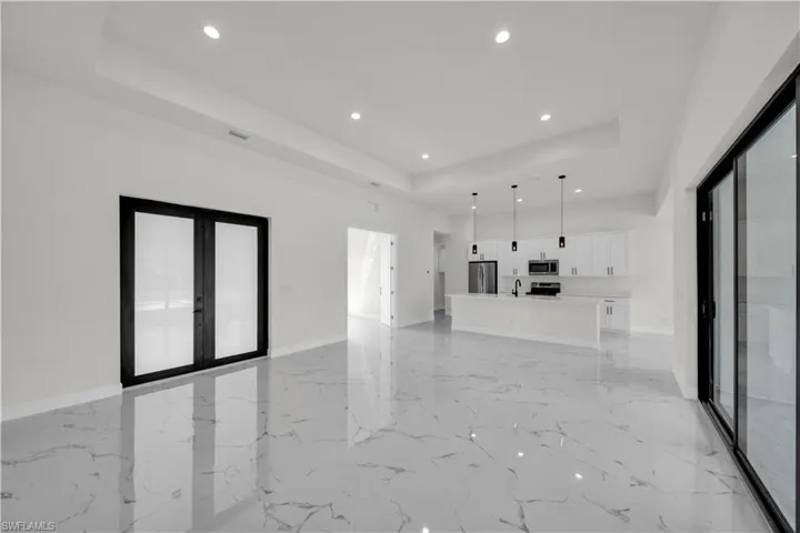 Unfurnished living room with baseboards, french doors, recessed lighting, and a raised ceiling