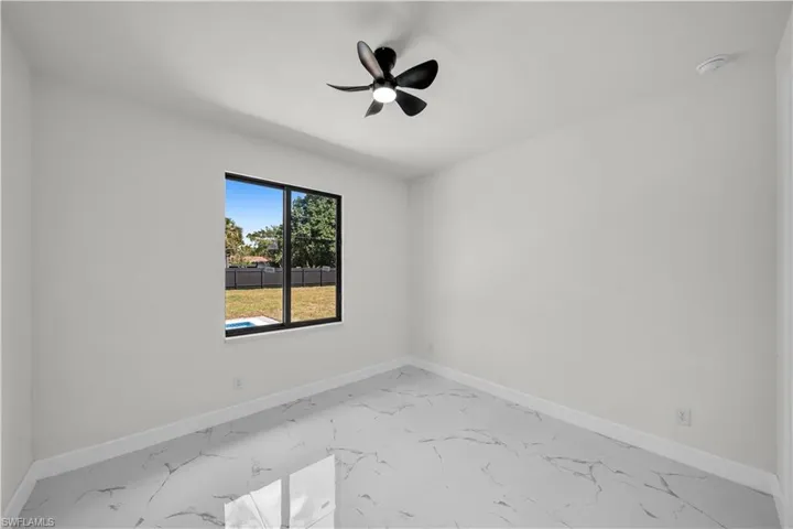 Spare room featuring a ceiling fan, marble finish floor, and baseboards
