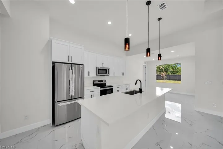 Kitchen featuring a sink, appliances with stainless steel finishes, marble finish floor, visible vents, and white cabinets