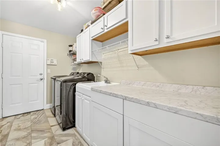 Laundry area with washer and dryer, cabinet space, and light marble finish flooring
