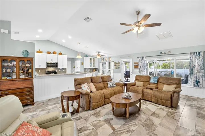 Living room with a ceiling fan, light marble finish flooring, high vaulted ceiling, and recessed lighting