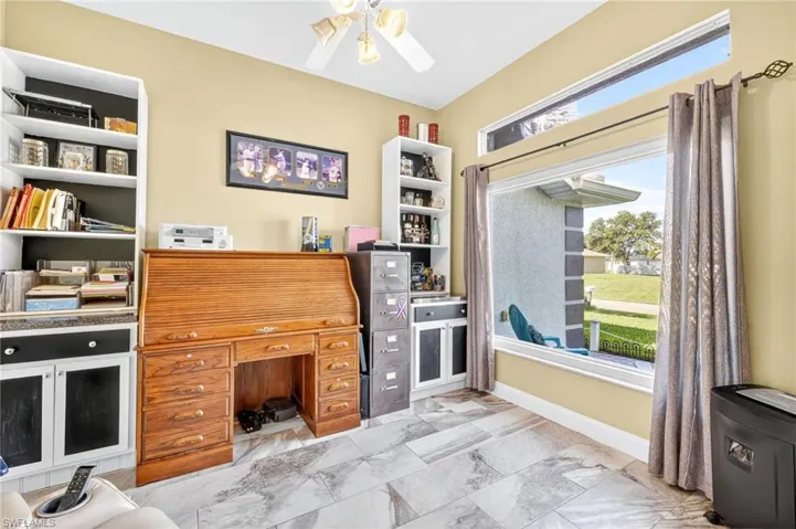 Office with a ceiling fan and light marble finish floors