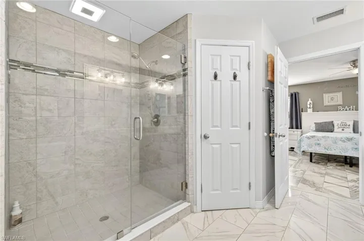Full bath featuring ensuite bathroom, a shower stall, marble look tiles, and ceiling fan