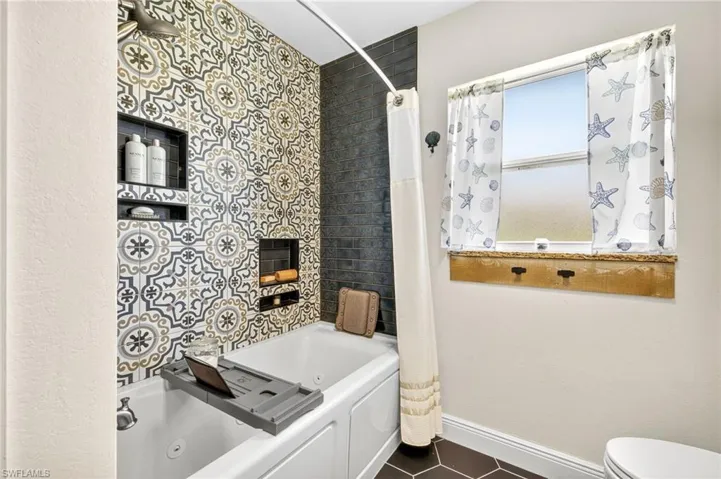 Bathroom with tile patterned flooring and a combined bath / shower with jetted tub
