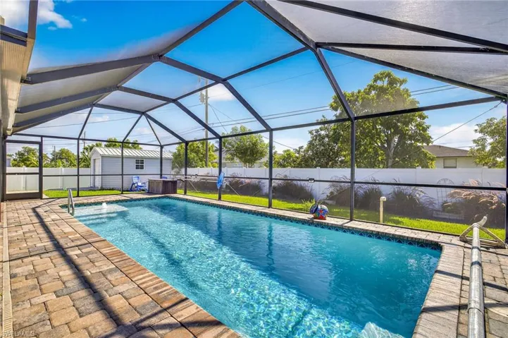 View of pool featuring a fenced backyard, a patio, a storage unit, and a lanai