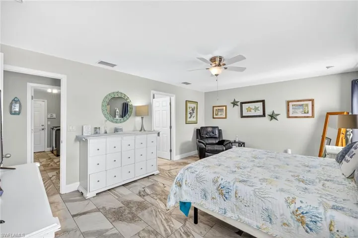 Bedroom with a ceiling fan and light marble finish flooring
