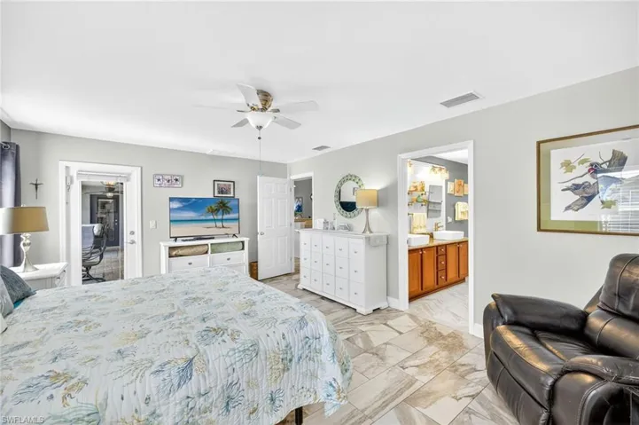 Bedroom with ensuite bath, light marble finish flooring, and a ceiling fan