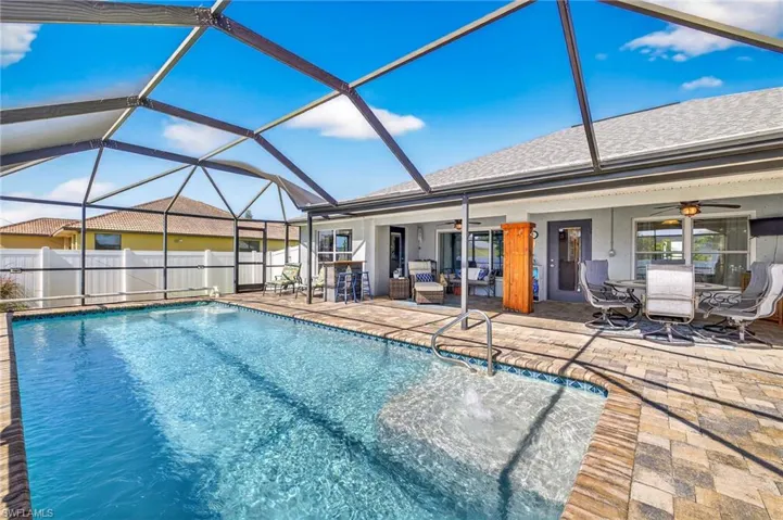 View of swimming pool featuring ceiling fan, a patio, outdoor dining area, and glass enclosure