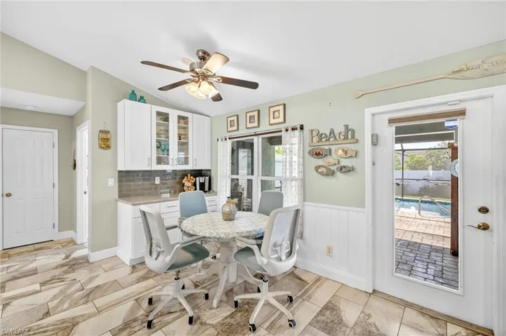 Dining room with lofted ceiling, ceiling fan, and wainscoting