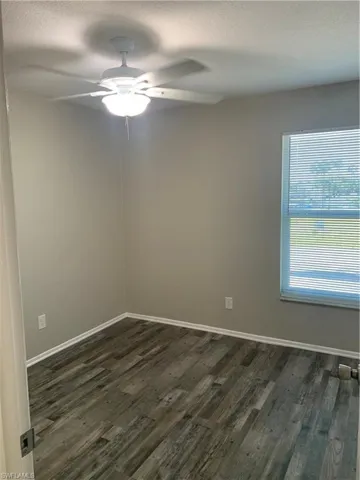 Guest bedroom featuring ceiling fan, a textured ceiling, and dark wood-type flooring