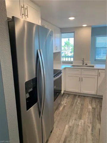 Kitchen with wood-type flooring, white cabinetry, sink, and stainless steel appliances