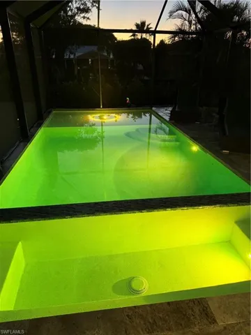 Pool at dusk featuring a sunroom, glass enclosure, and an outdoor pool
