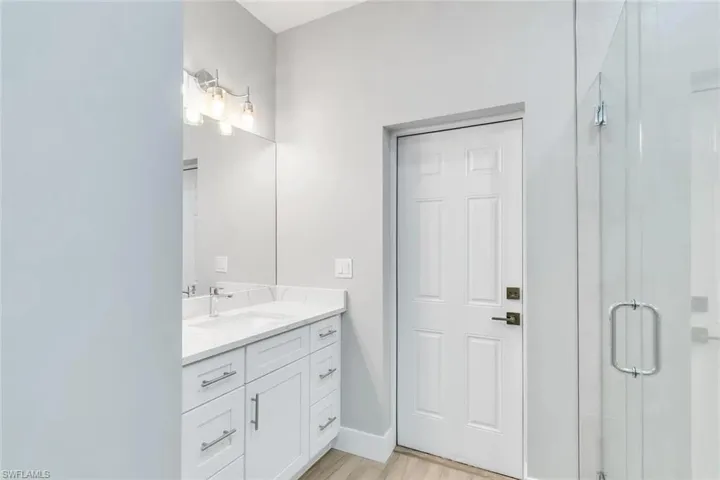 Full bath with a shower stall, vanity, and light wood-style flooring