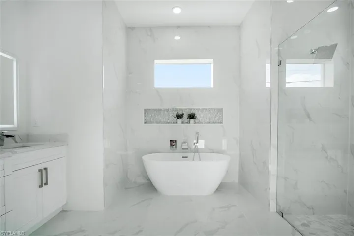 Bathroom featuring tile patterned floors, tile walls, vanity, and separate shower and tub