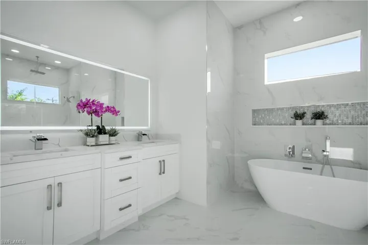 Bathroom featuring tile patterned floors, tile walls, a healthy amount of sunlight, and double vanity