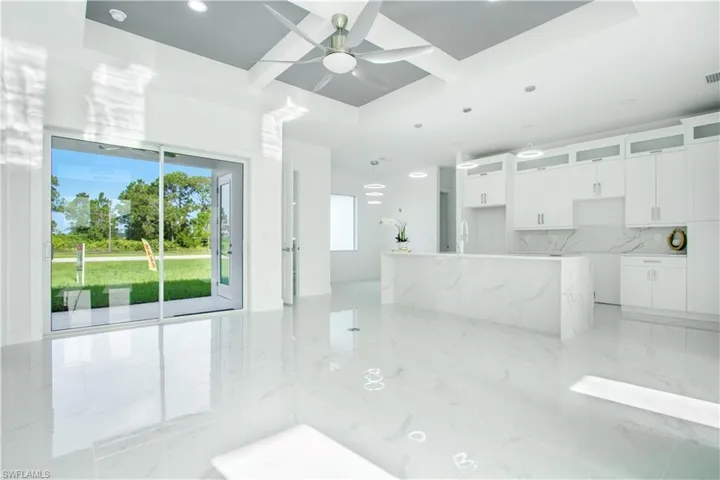 Unfurnished living room featuring light tile patterned flooring, sink, ceiling fan, and a raised ceiling
