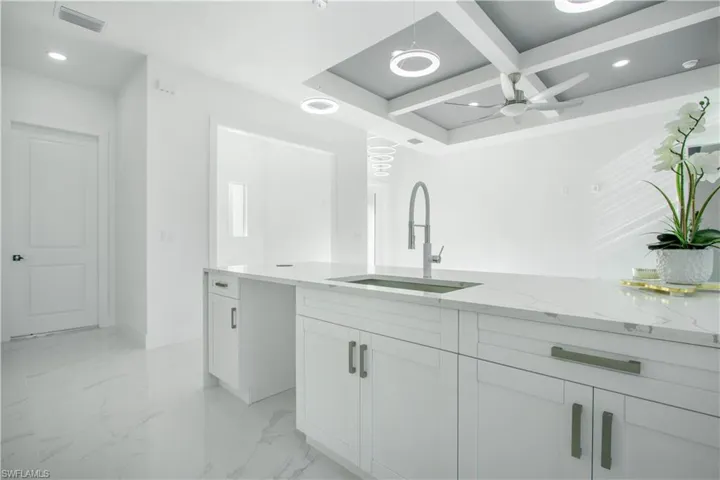 Bathroom with ceiling fan, coffered ceiling, sink, and tile patterned flooring