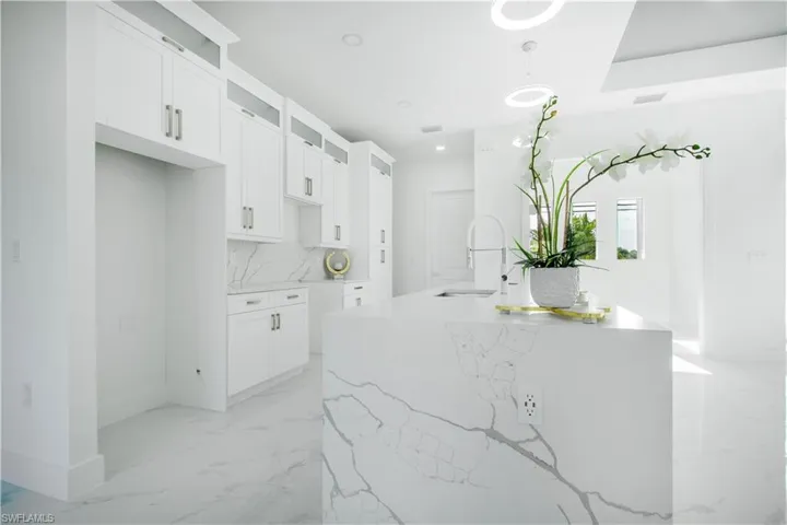 Kitchen featuring light tile patterned floors, sink, hanging light fixtures, and light stone countertops