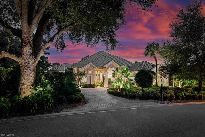View of front of property featuring a standing seam roof, curved driveway, and a metal roof