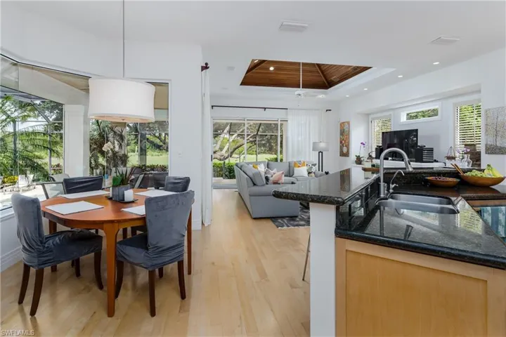 Dining room featuring a tray ceiling, light wood-type flooring, recessed lighting, and a ceiling fan