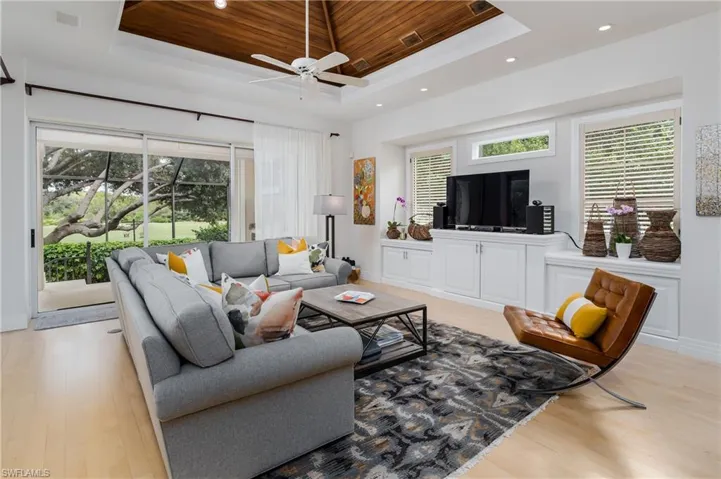Living area with a raised ceiling, recessed lighting, light wood-style flooring, ceiling fan, and wood ceiling