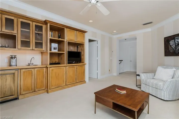 Living room with crown molding, light carpet, and ceiling fan