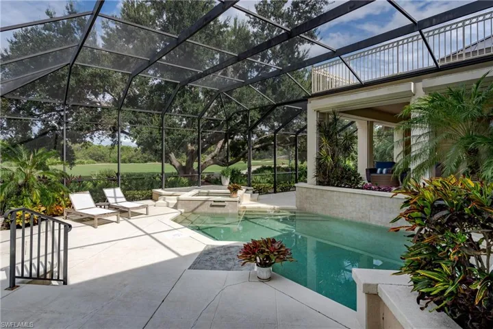 View of pool featuring a patio, glass enclosure, and a pool with connected hot tub