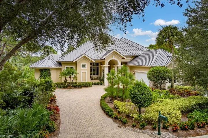 View of front of home with a standing seam roof, an attached garage, a metal roof, and decorative driveway