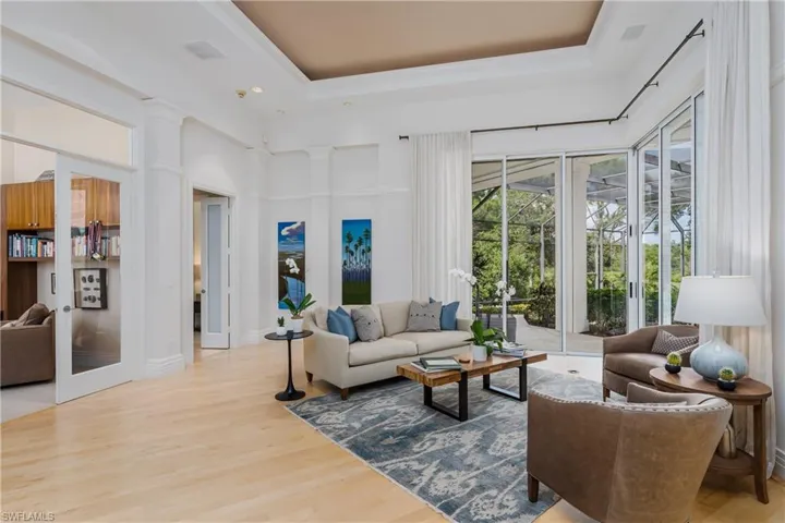 Living area with wood finished floors, a high ceiling, and a tray ceiling
