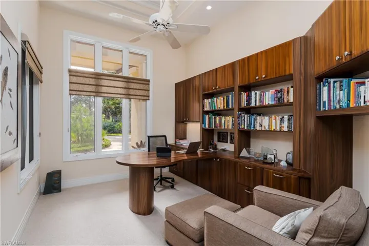 Office space with light carpet, ceiling fan, and a towering ceiling