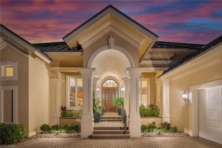 Exterior entry at dusk featuring stucco siding, a standing seam roof, a metal roof, decorative driveway, and an attached garage