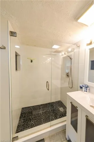 Bathroom featuring vanity, a shower with shower door, and a textured ceiling