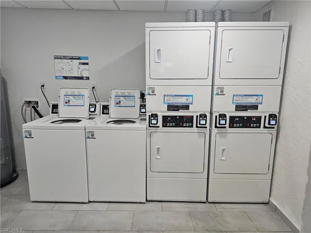 Laundry area with light tile patterned flooring, washer and dryer, and stacked washer and clothes dryer