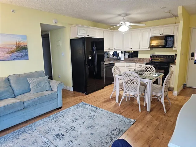 Kitchen featuring wrap around cabinietry & granite counters, Samsung appliances, ceiling fan, light wood-type flooring, a textured ceiling, and dining space