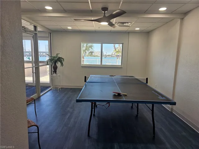 Game room featuring a drop ceiling, ceiling fan, a water view, and dark wood-type flooring