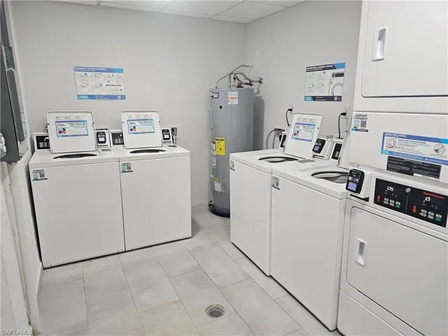 Clothes washing area featuring independent washer and dryer, light tile patterned floors, stacked washer and clothes dryer, and water heater