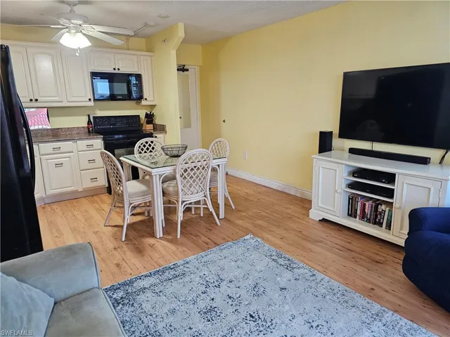 Kitchen featuring full size appliances, ivory cabinets, ceiling fan, light wood-type flooring, and a textured ceiling