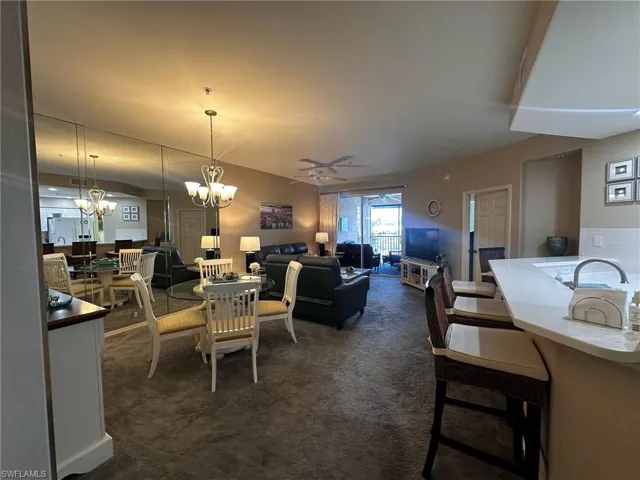 Dining room with a ceiling fan, a chandelier, and dark colored carpet