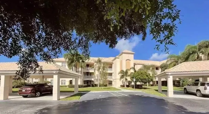 View of apartment building / complex featuring covered and uncovered parking