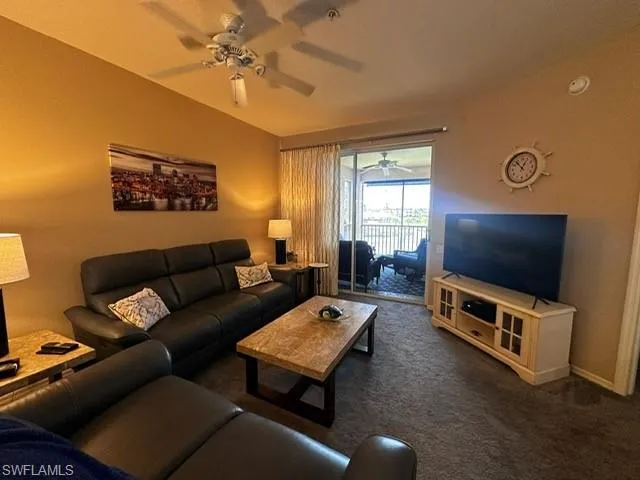 Living area featuring dark carpet and ceiling fan