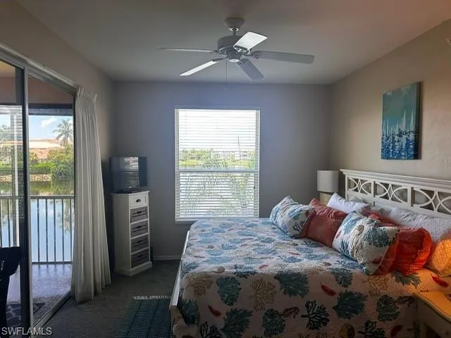 Bedroom with access to outside, dark colored carpet, and a ceiling fan