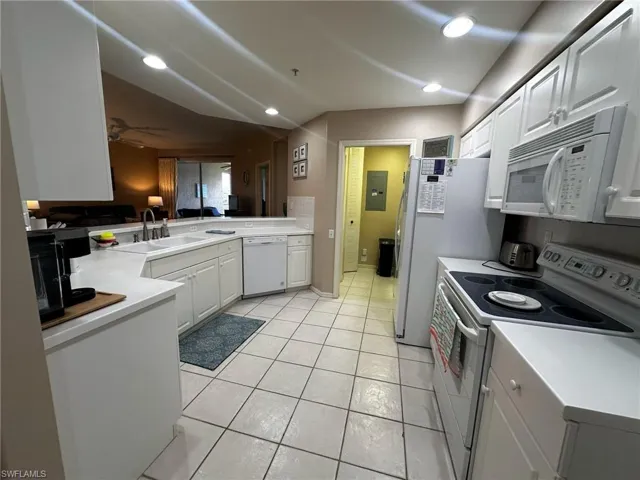 Kitchen featuring white appliances, light countertops, white cabinetry, recessed lighting, and light tile patterned floors