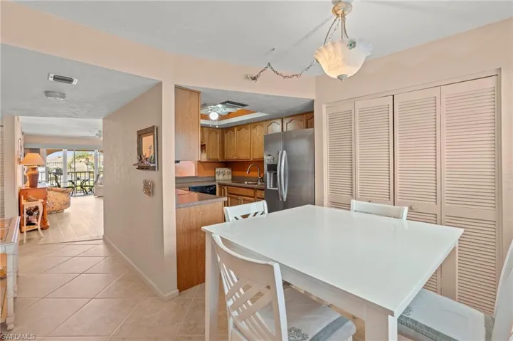 Kitchen featuring stainless steel refrigerator with ice dispenser, light tile patterned floors, brown cabinetry, and a ceiling fan