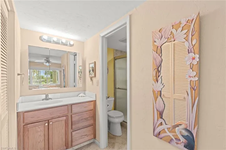 Full bathroom with vanity, a textured ceiling, a stall shower, a closet, and a ceiling fan