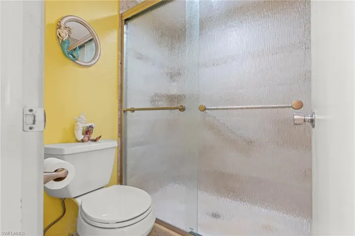 Full bath featuring newer title shower and toilet
