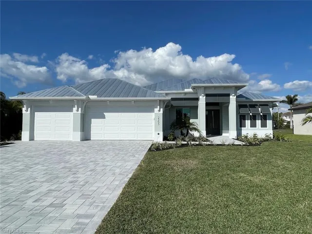 View of front of house featuring a metal roof, a garage, a front yard, decorative driveway, and a standing seam roof